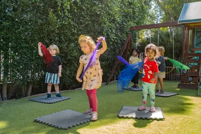 Preschoolers waving colorful scarves during an outdoor music and dance activity